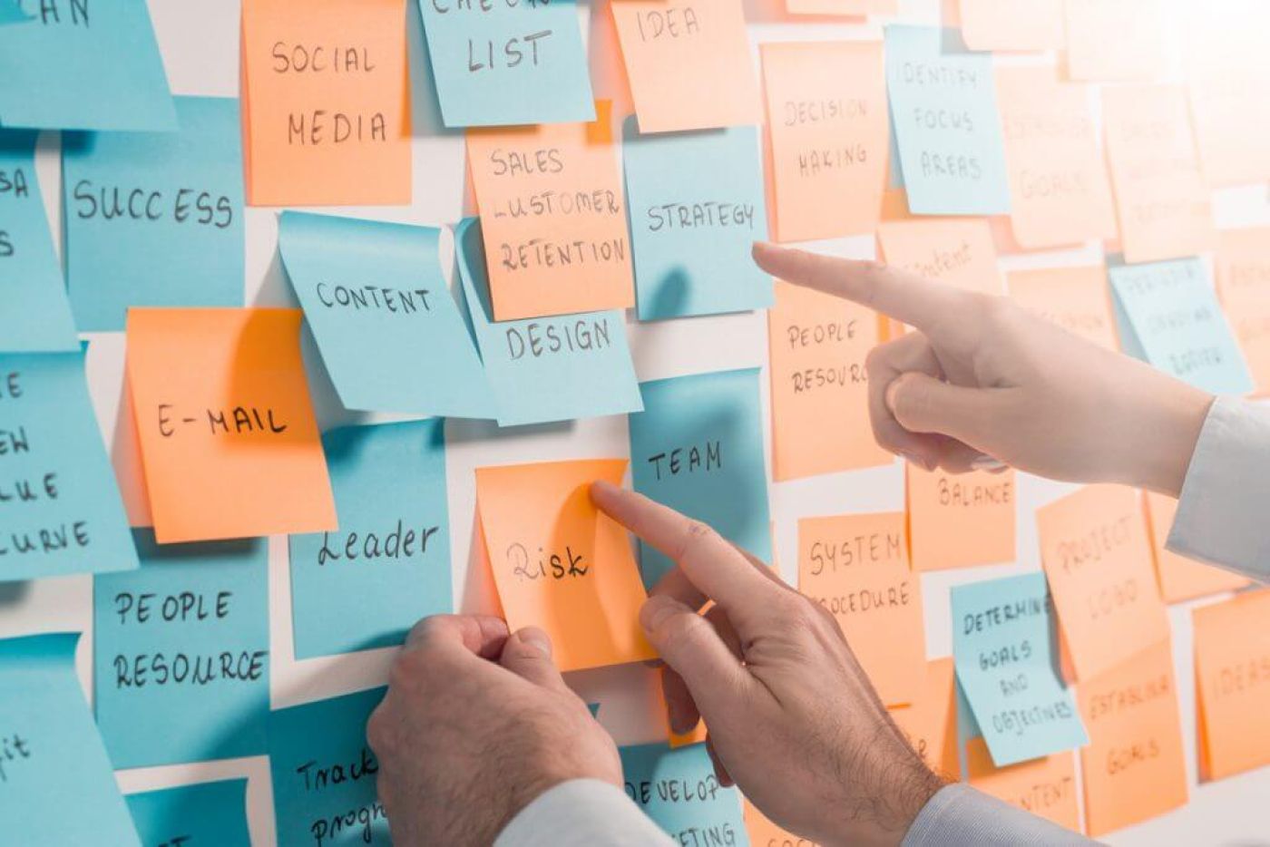 Haende bringen Klebezettel an. Führen mit Teamzielen.